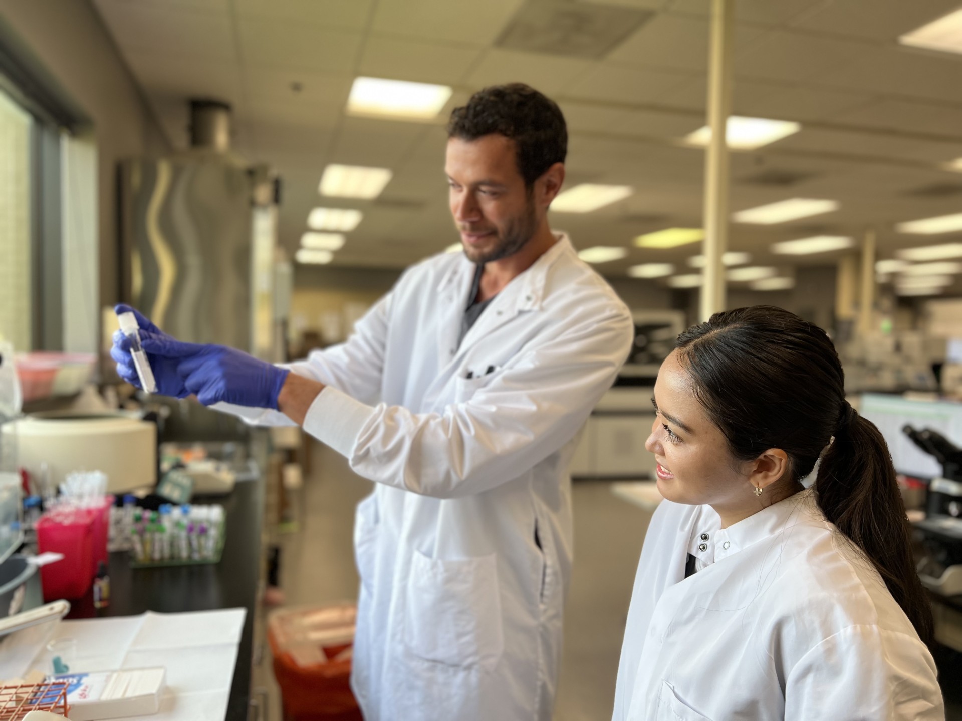Lab workers in white lab coat looking at tube